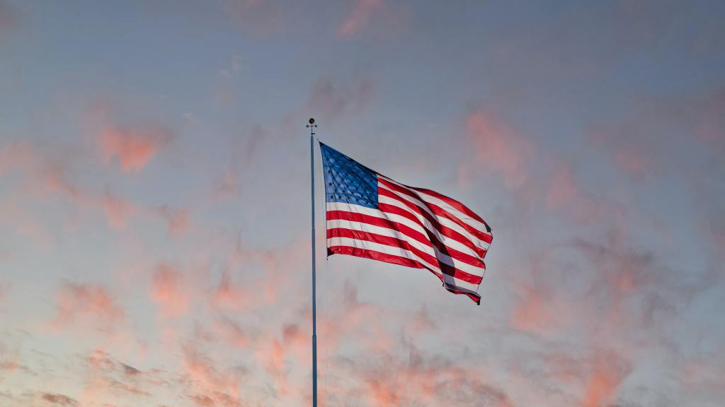 US American Flag on pole on a sunset sky.