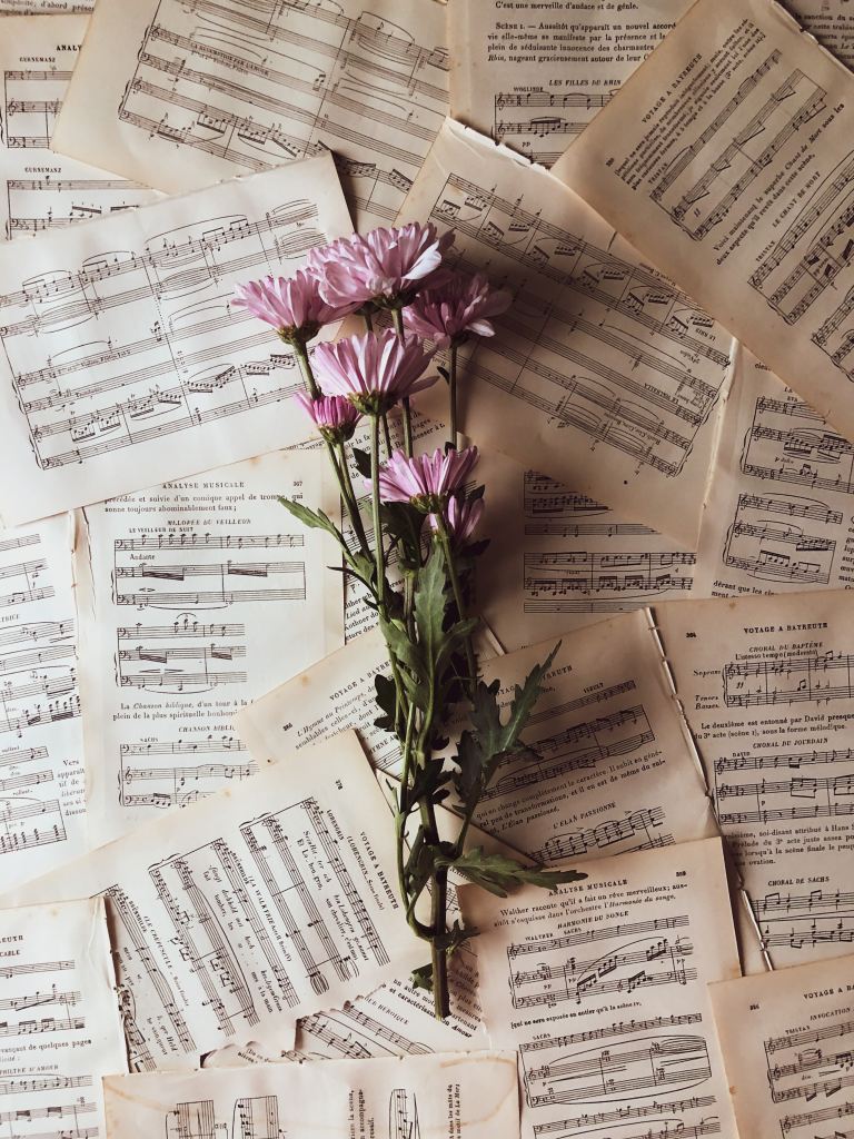 Flowers on a pile of assorted sheet music.