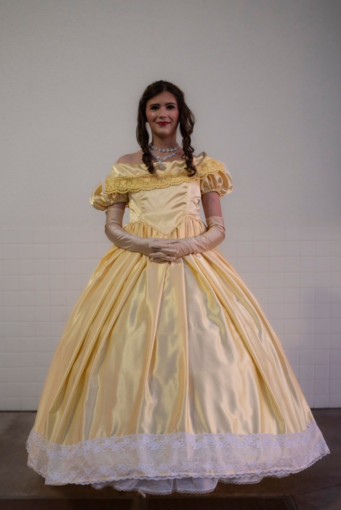 woman in a light yellow gown standing in  a white background